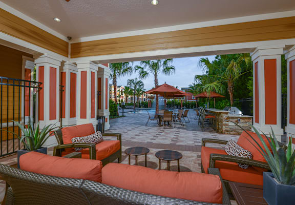 a patio with orange couches and tables and a pool at The Amalfi Clearwater Luxury Apartments in FL
