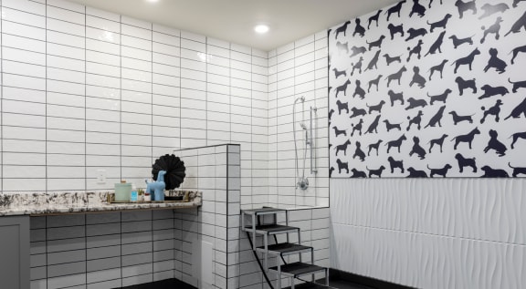 a bathroom with white tiles and a black and white pattern on the wall
