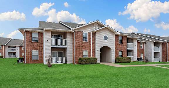 Apartment complex with red brick buildings and green lawns.