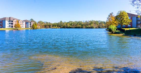 A serene lake with a row of buildings in the background.