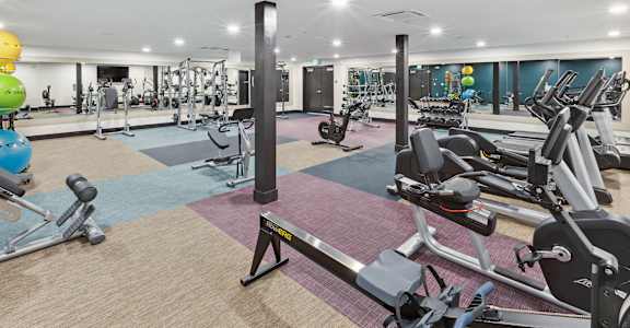 A gym with a variety of equipment including weights and cardio machines.