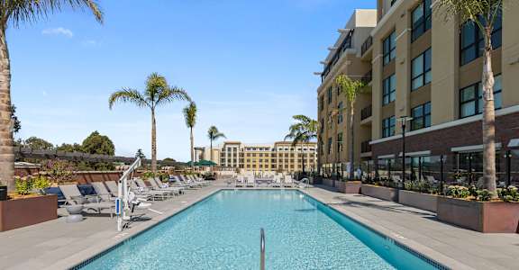 A large outdoor swimming pool surrounded by palm trees and lounge chairs.