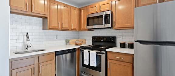 a kitchen with wooden cabinets and stainless steel appliances at Fox Run Apartments, St. Charles, Illinois
