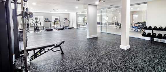 a gym with weights and cardio equipment on the floor and a glass wall