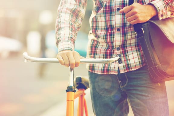 Cropped image of man in plaid shirt standing next to bicycle