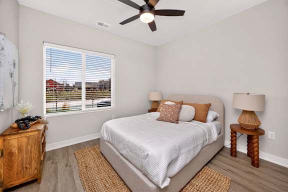 A bedroom with a bed, two nightstands, and a ceiling fan.