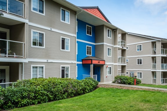 an apartment building with a green yard in front of it