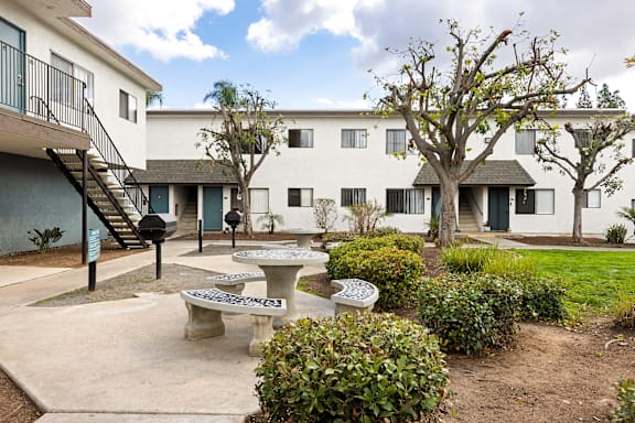 A courtyard with a bench, a table and a tree.