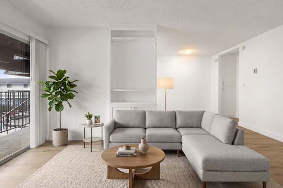 A living room with a grey sofa, a wooden table, and a potted plant.