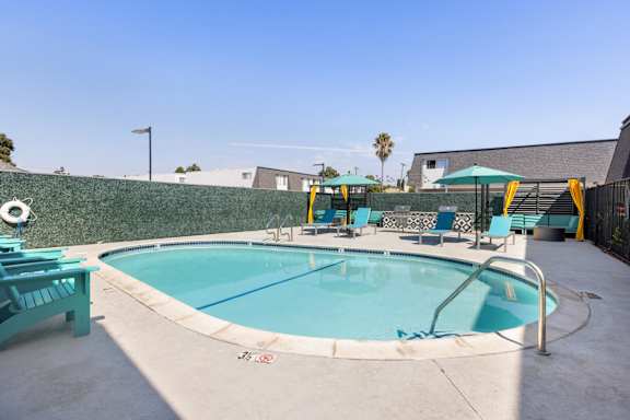 A small pool with a metal railing and a few chairs around it.