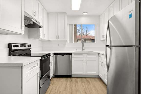 A modern kitchen with white cabinets and stainless steel appliances.