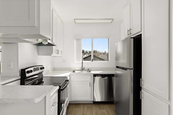 A modern kitchen with white cabinets and stainless steel appliances.