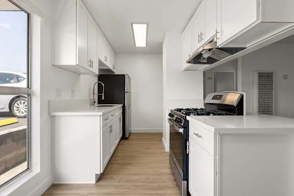 A modern kitchen with white cabinets and black appliances.
