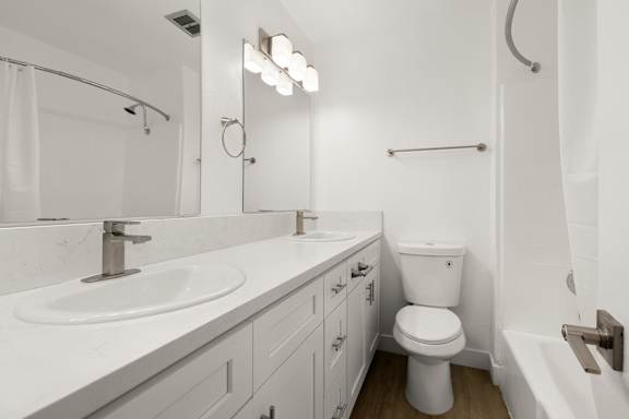 A white bathroom with a toilet, sink, and shower.