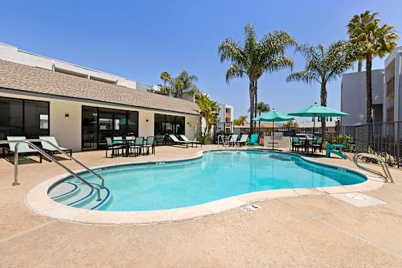 A swimming pool surrounded by chairs and umbrellas.