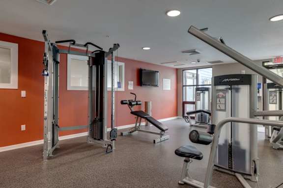 A gym with a variety of equipment including a squat rack, bench, and weights.