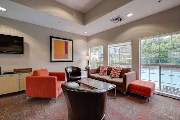 A living room with a television, couch, and chairs.