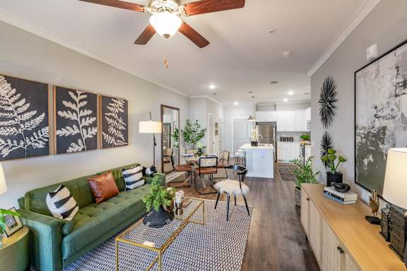 a living room with a green couch and a ceiling fan
