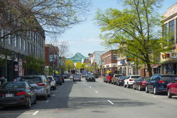 a city street with cars parked on the side of the road and a green bridge