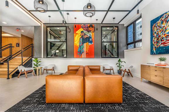 A modern living room with a large orange sofa and a painting on the wall.