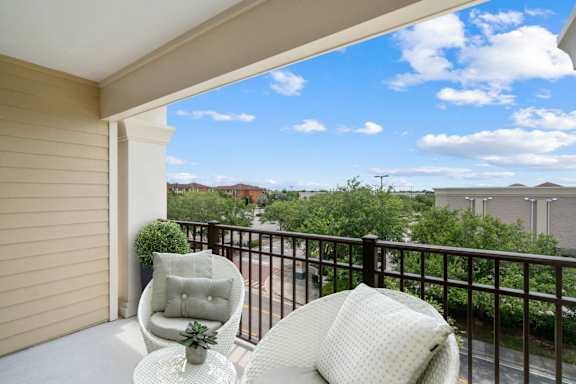 A balcony with a chair and a table with a plant on it.