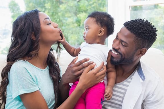 a man and woman holding a baby on a couch
