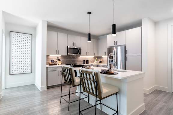 A modern kitchen with a white countertop and stainless steel appliances.