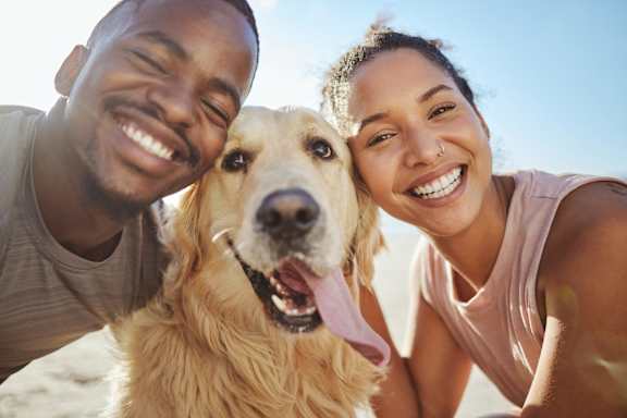 Man and Woman Smiling while Outside with Pet Dog