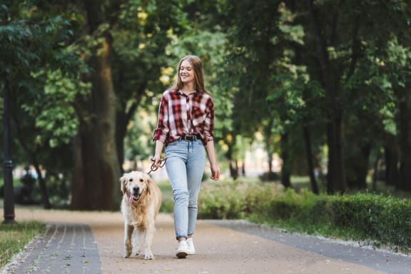 Woman Smiling while Walking Her Dog in Park