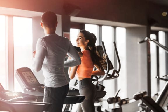 Man and Woman Running on Treadmill in Fitness Center Together