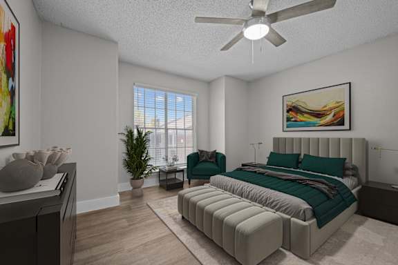 A bedroom with a large bed, a ceiling fan, and a painting on the wall.