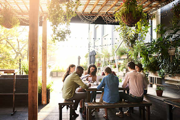 A group of people are sitting at a table in a restaurant with wooden tables and chairs.