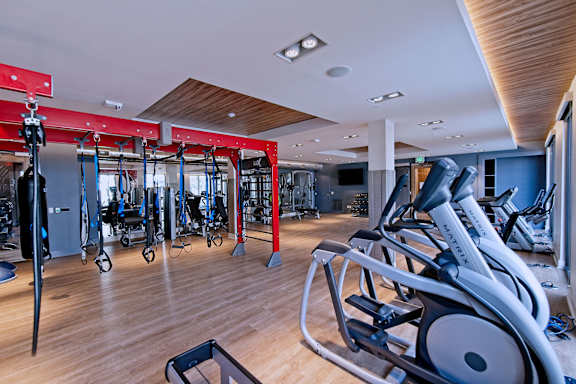 A gym with a variety of exercise equipment including treadmills, stationary bikes, and weight machines.