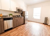 Thumbnail 5 of 8 - A kitchen with wooden floors and stainless steel appliances.