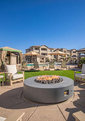 A fire pit sits in the middle of a patio surrounded by chairs.
