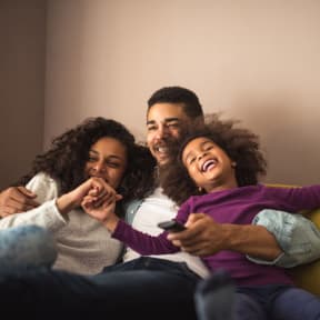 Family Smiling while Sitting on Sofa Together