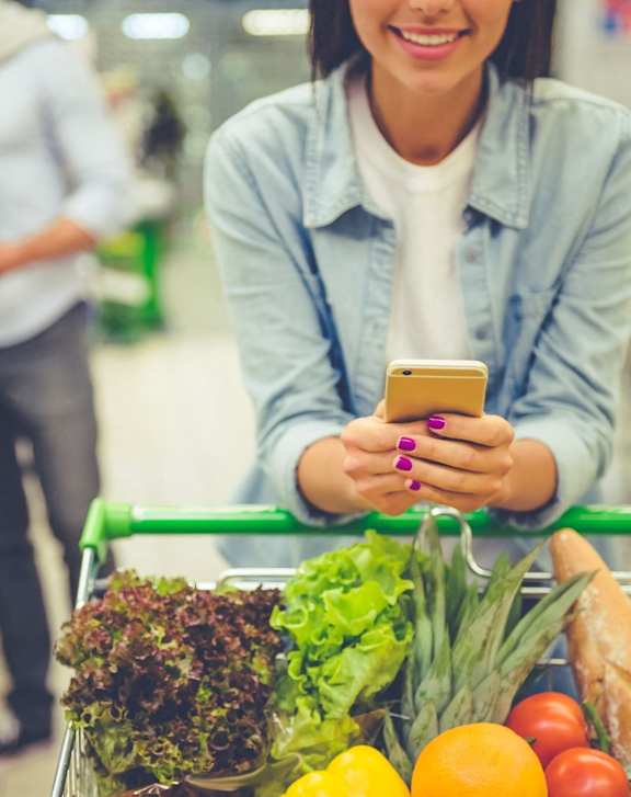 Woman Looking at Her Phone while Grocery Shopping