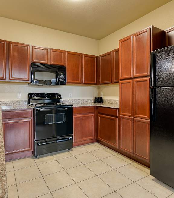 A kitchen with brown cabinets and black appliances.