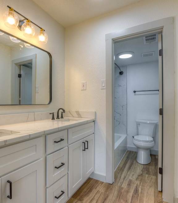 A bathroom with a white sink and a mirror above it.at The Garden District Apartments, Tennessee