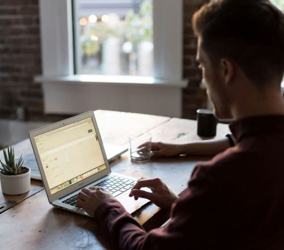 a man sitting at a table using a laptop computer