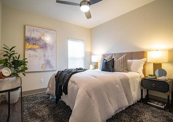 A bedroom with a bed, nightstand, and a ceiling fan.
