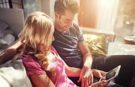 couple sitting on a porch looking at a tablet