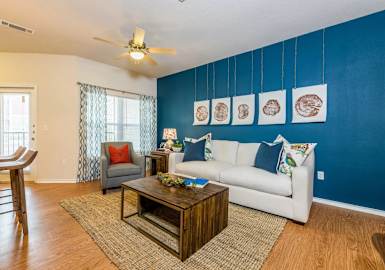 a living room with a white couch and a blue accent wall at Villa Espada Apartments, San Antonio, Texas
