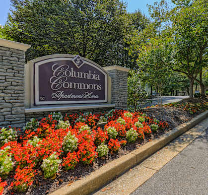 a sign commons sits in front of a garden of flowers