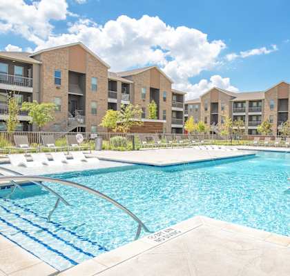 A large swimming pool in front of apartment buildings.