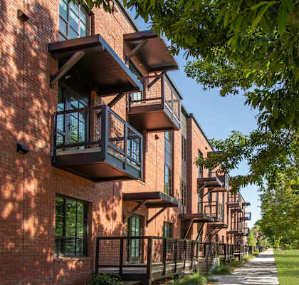A row of apartment buildings with balconies and trees in the foreground.