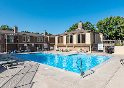 A swimming pool with a diving board and a building in the background.