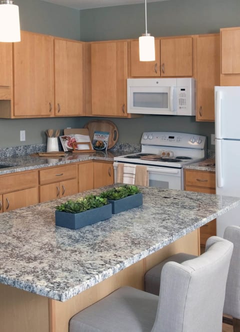 a kitchen with white appliances and granite counter tops at The Legends of Cottage Grove 55+ Apartments, Minnesota