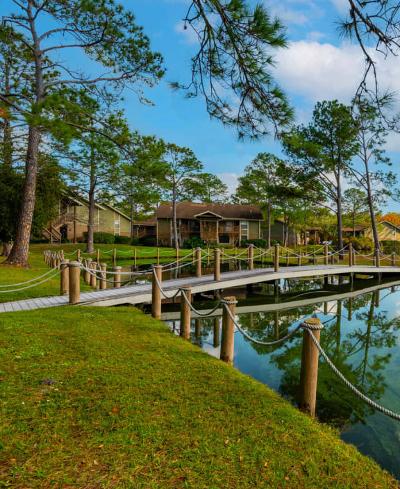 A wooden bridge over a calm body of water with a rope barrier. at Whisper Lake Apartments, Winter Park, 32792