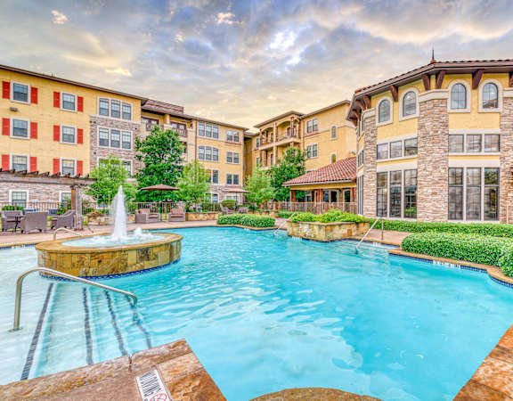 a swimming pool with a fountain and a building in the background